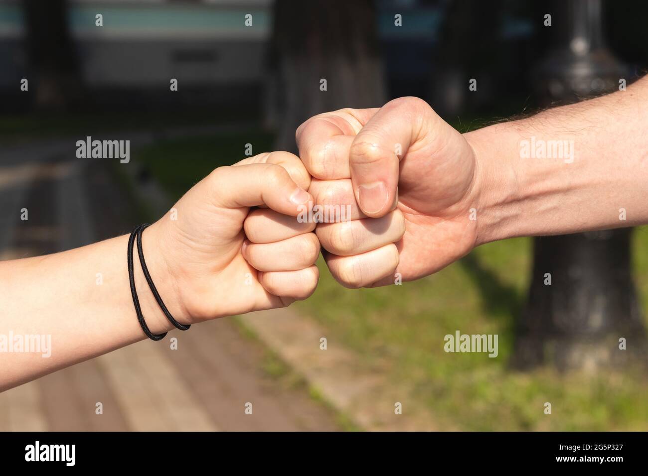 Father and child daughter bumping fists against blurred nature outdoor background. Trust, care and parenting family, father's day concept Stock Photo