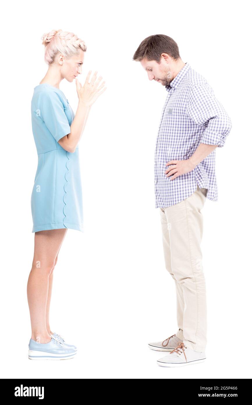 Vertical full length side view studio shot of angry young adult woman quarrelling with her husband, white background Stock Photo