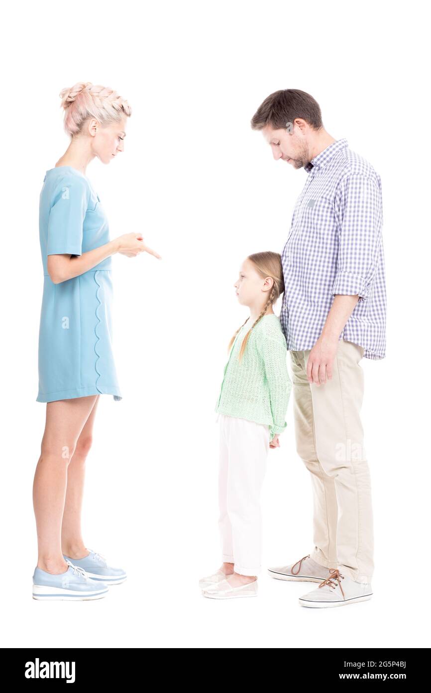Vertical studio side view portrait of young adult parents telling their daughter off for bad behavior, white background Stock Photo