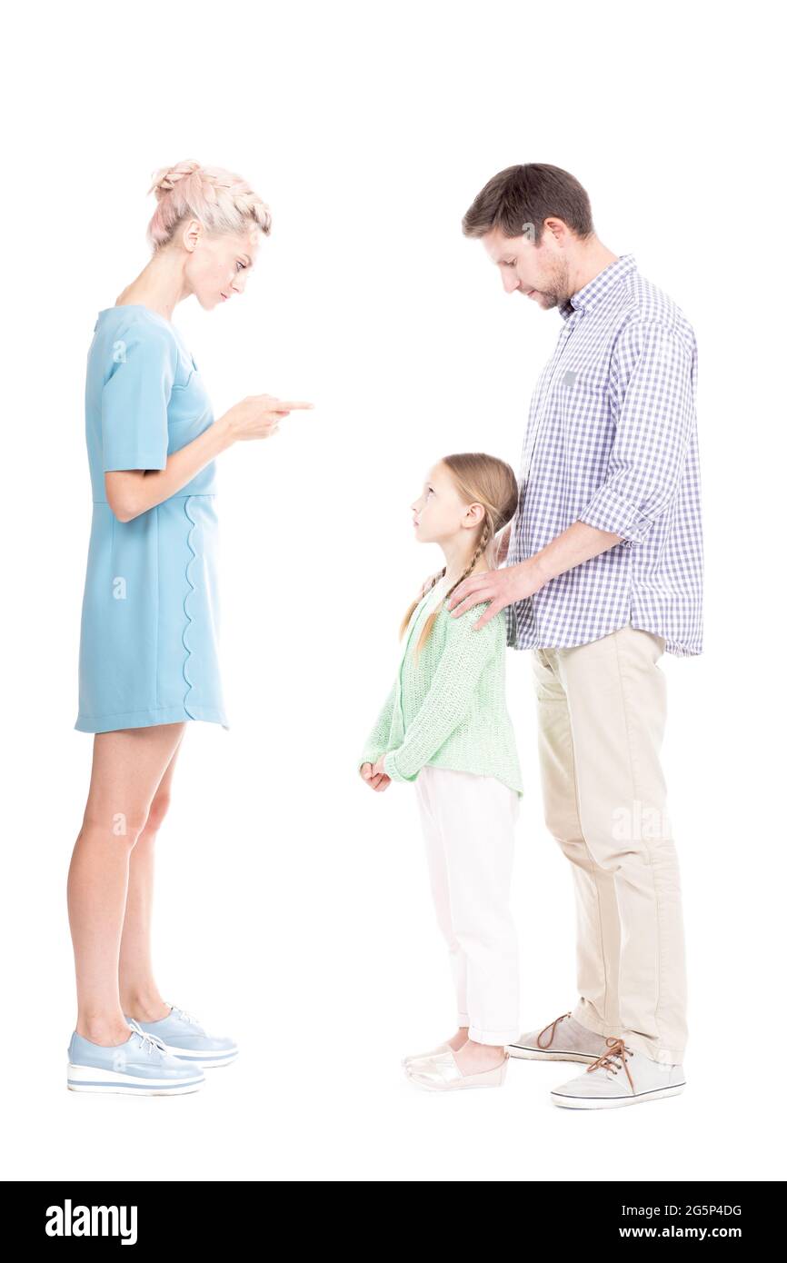 Vertical studio side view portrait of young adult parents telling their daughter off for bad behavior, white background Stock Photo