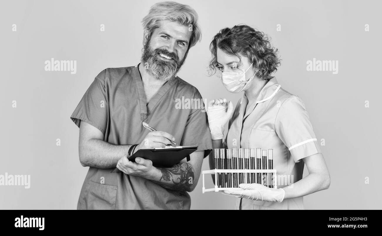 making notes. doctors wear respirator mask. infection vaccine and blood test. Medical professional working. medical couple use testing tube Stock Photo