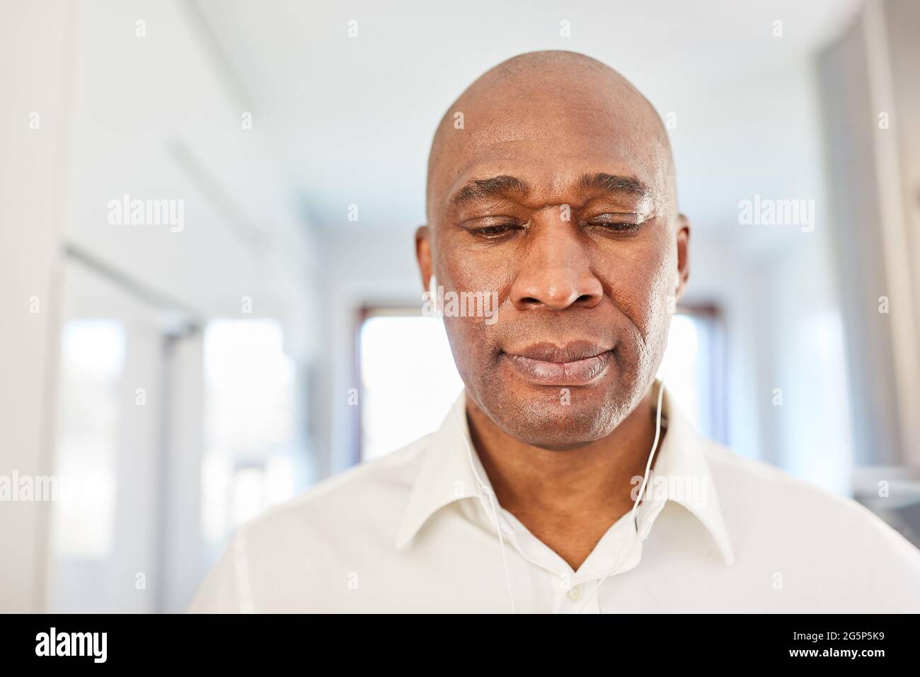 African business man with in-ear headphones in the home office during video chat Stock Photo
