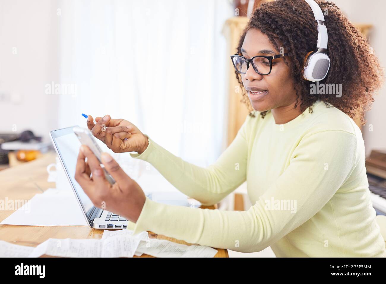 Business woman at the computer with headphones and smartphone during video chat in the home office Stock Photo