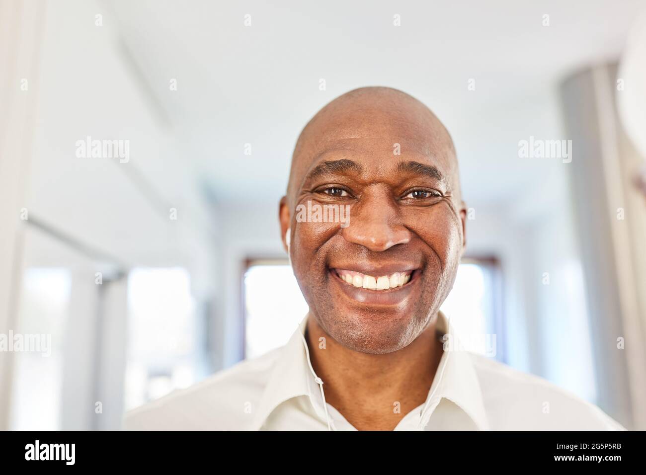 Portrait of a happy african man with in-ear headphones at home or in the home office Stock Photo