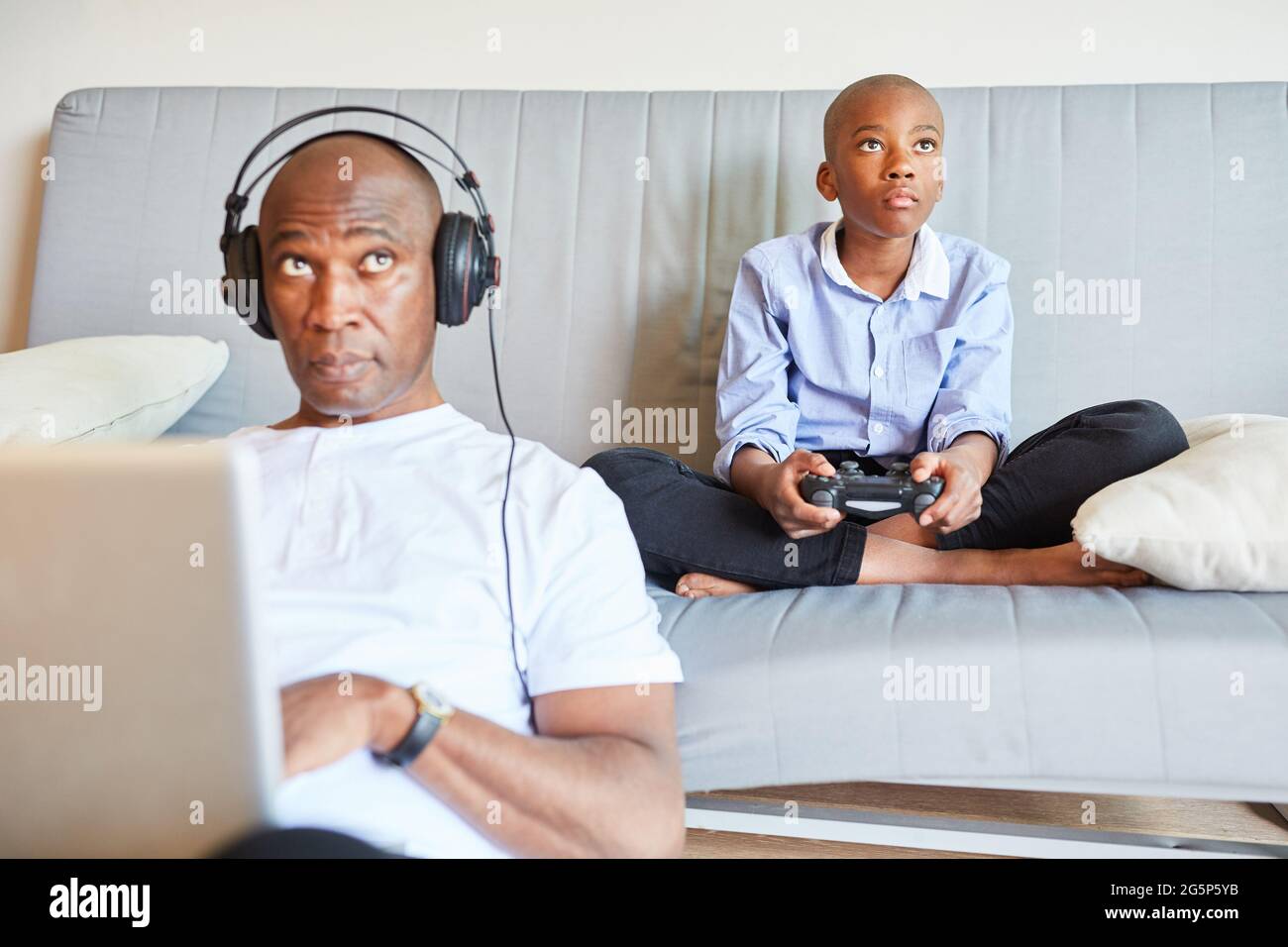 lazy teenager boy play computer games, sit in headphones, looking at screen  of laptop, free time at home Stock Photo