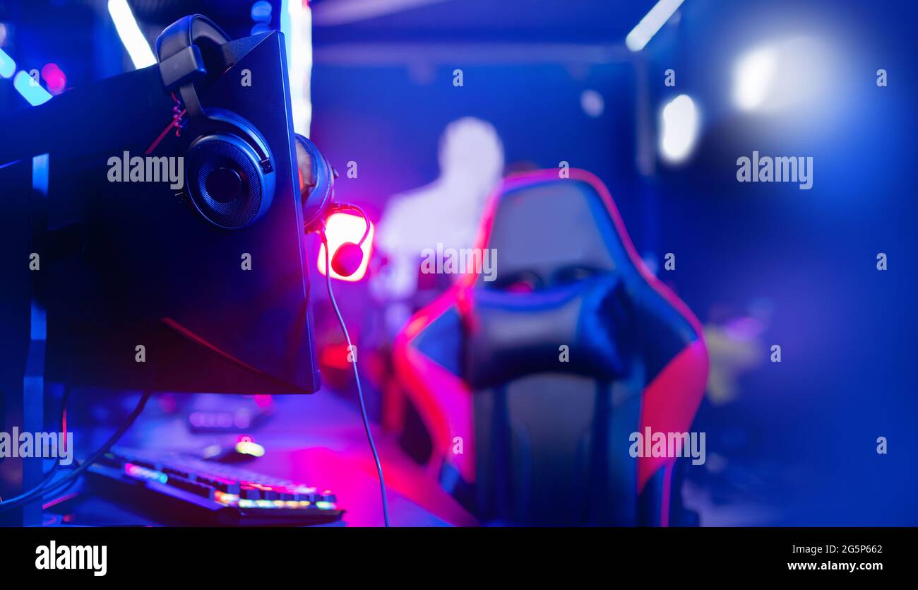 Happy professional player streaming esport tournament using microphone and  headphones, enjoying a multiplayer game. Competitive gamer playing online  video game at home. Neon color. Cyber sport concept Stock Photo