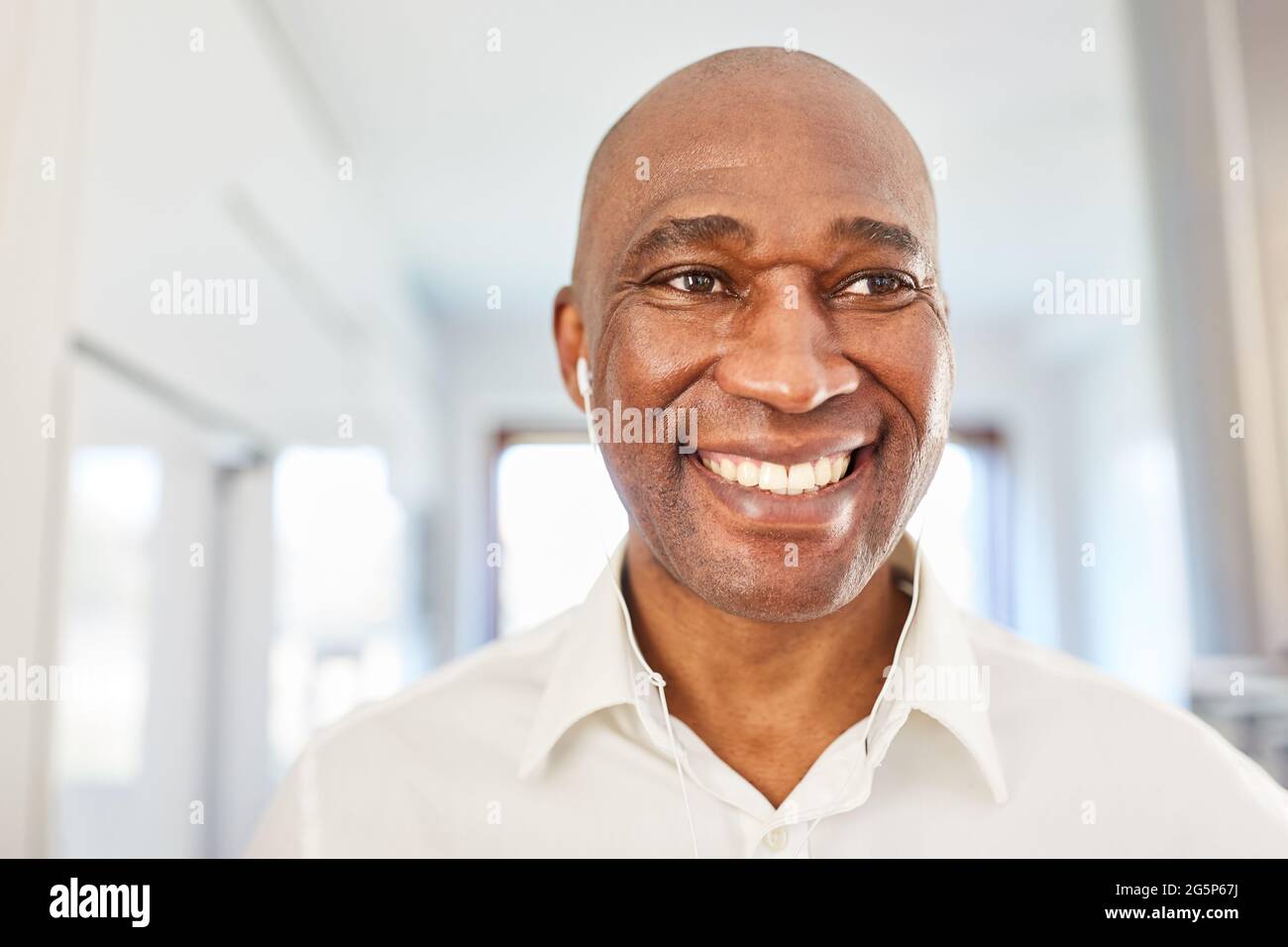 Smiling African Business Man With In-Ear Headphones At Home In The Home Office Stock Photo