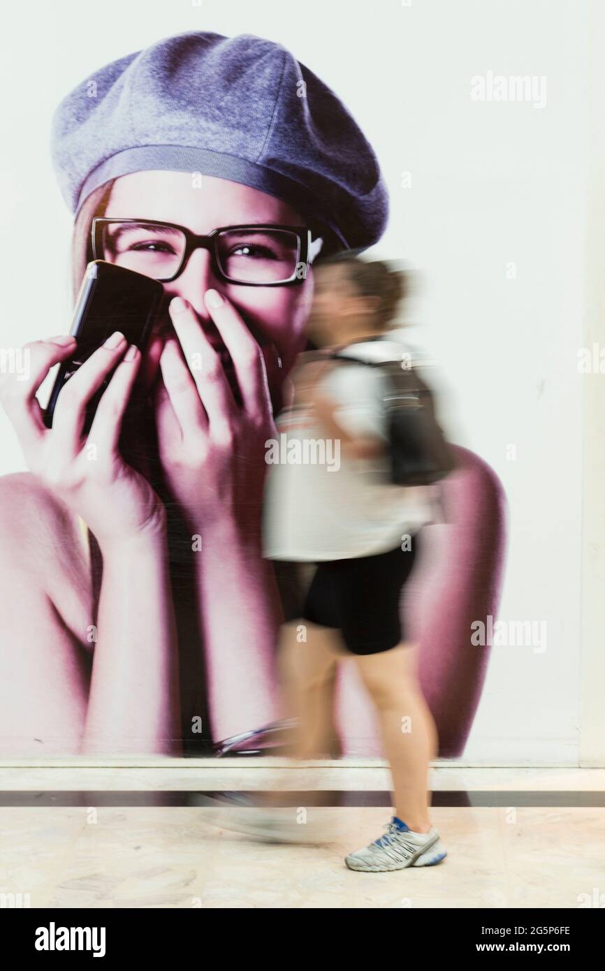 customer in a shopping mall have fun, walk around and shop, in front of a cell phone advertisement Stock Photo