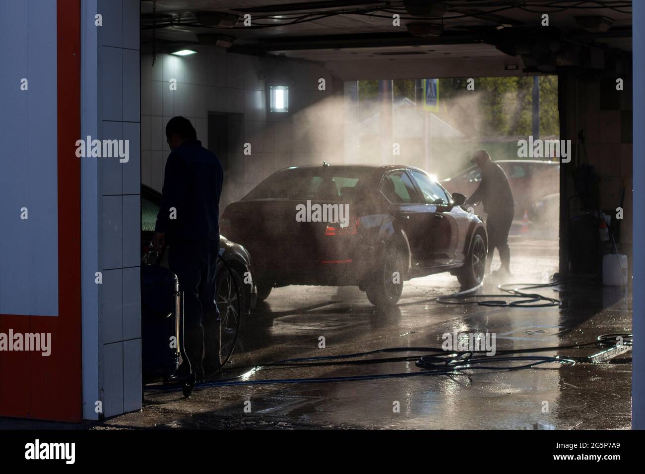 Car wash at a car wash. Workers wash their cars under the pressure of