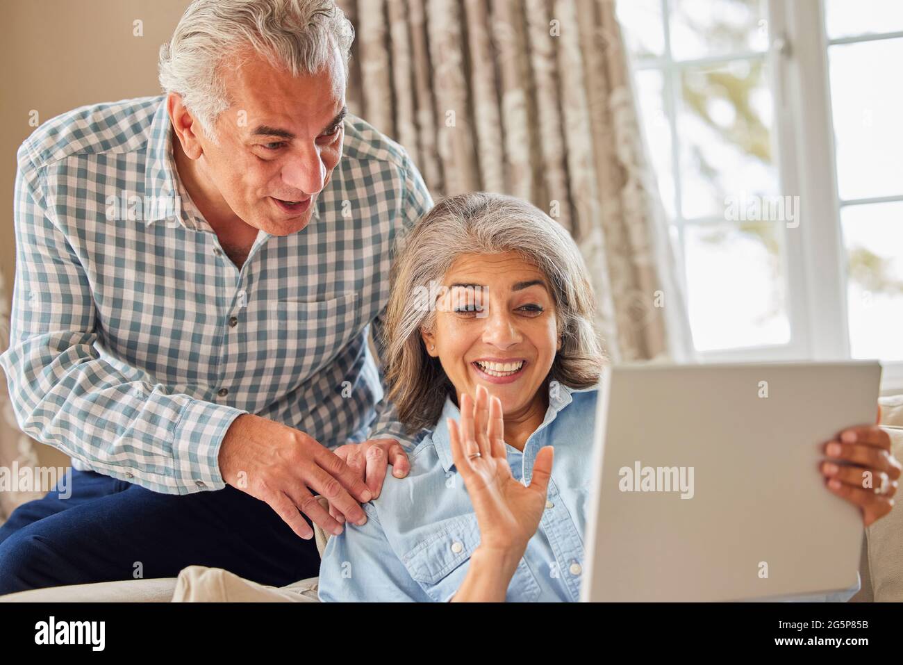 Mature Couple At Home Having Video Chat With Family Stock Photo