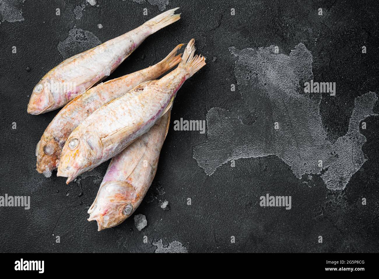 Frozen surmullet fish set, on black dark stone table background, top ...