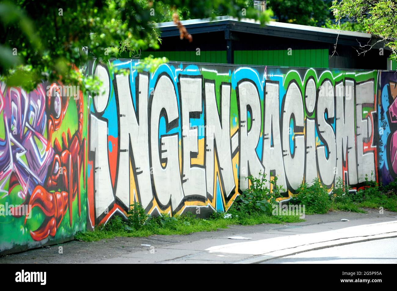 DENMARK. COPENHAGUEN. CHRISTIANA. VELO PASSING BY A MURAL SAYING 'STOP RACISM' (INGEN RACISM) IN THE DISTRICT OF CHRISTIANA. SINCE 1971, THIS FORMER M Stock Photo