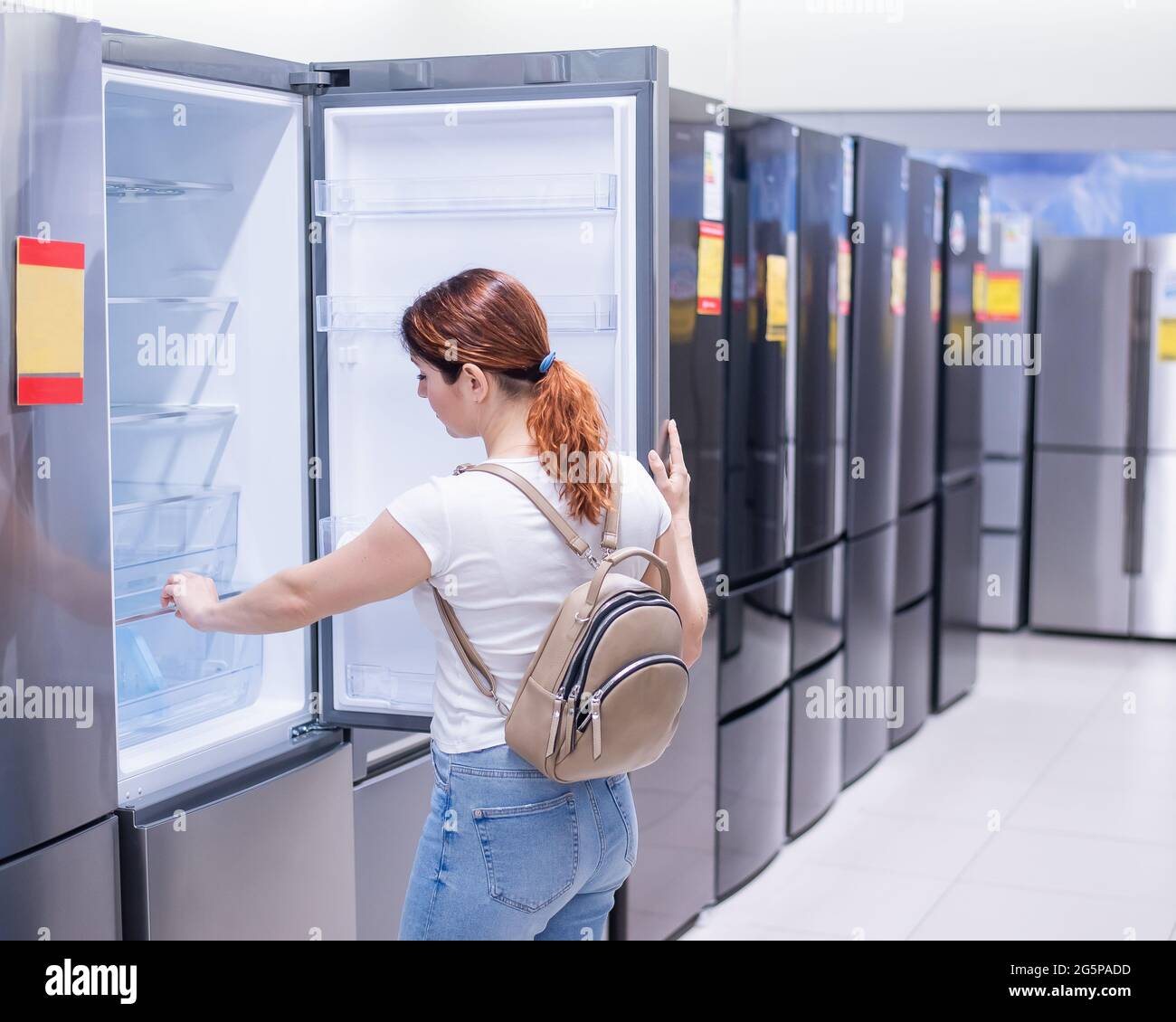 Caucasian woman chooses a refrigerator in a home appliance store Stock Photo