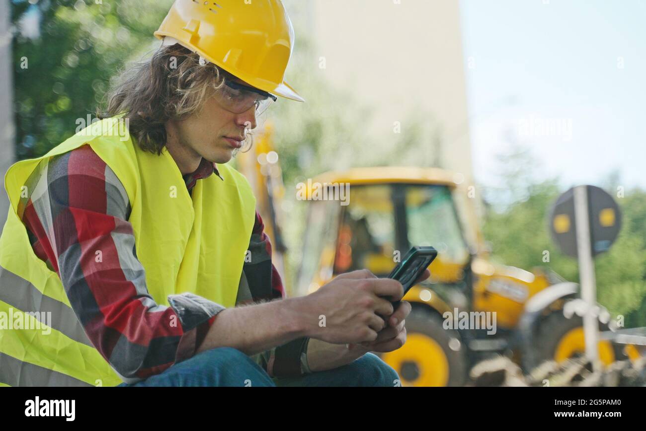 Tired male worker using smartphone on a break. Stock Photo