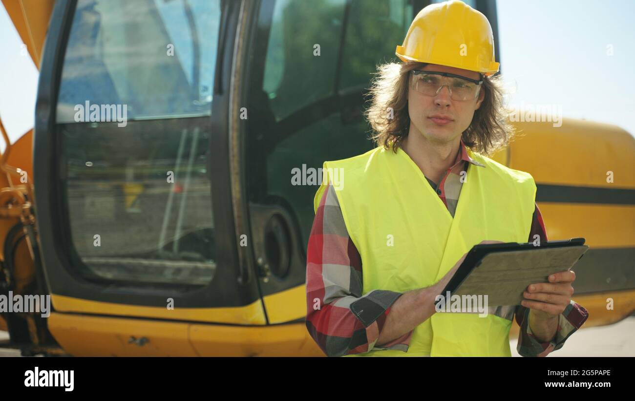 Excavator operator in hard hat using tablet pc Stock Photo - Alamy