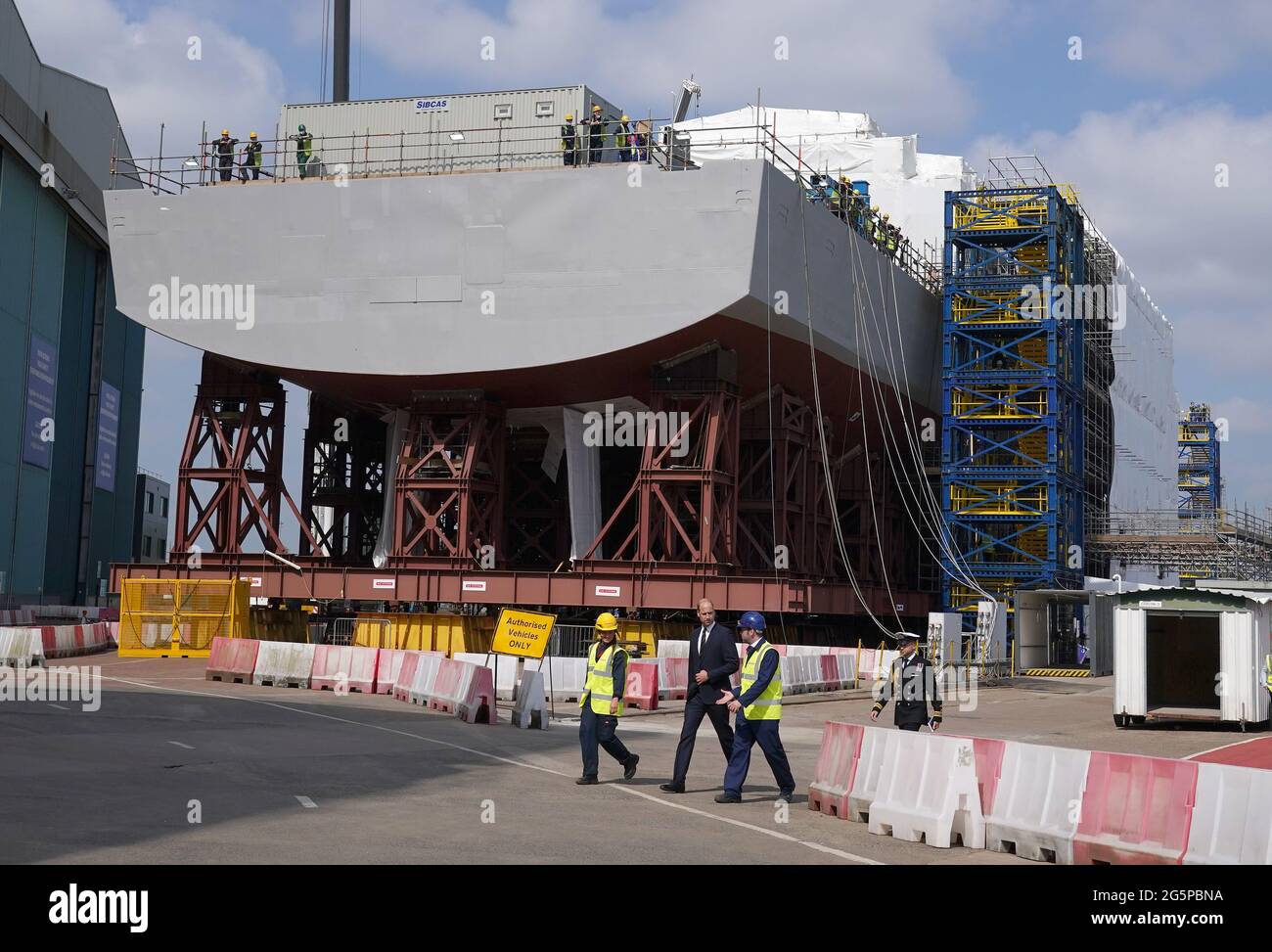 The Duke of Cambridge, known as the Earl of Strathearn in Scotland, alongside apprentice Cara Shannon as they view construction work on HMS Glasgow(in the background) during a visit to the BAE Systems shipyard in Glasgow, as part of a trip to Scotland for Holyrood Week. Picture date: Tuesday June 29, 2021. Stock Photo
