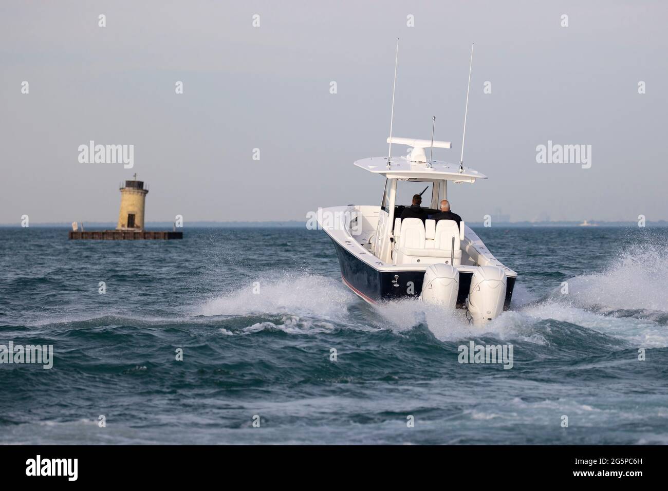 Center console boat speeding toward a lighthouse. Stock Photo