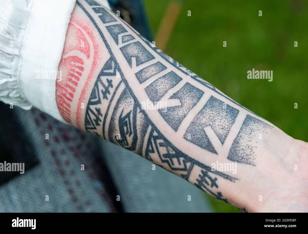 Tattoos on female arm in black and red ink Stock Photo
