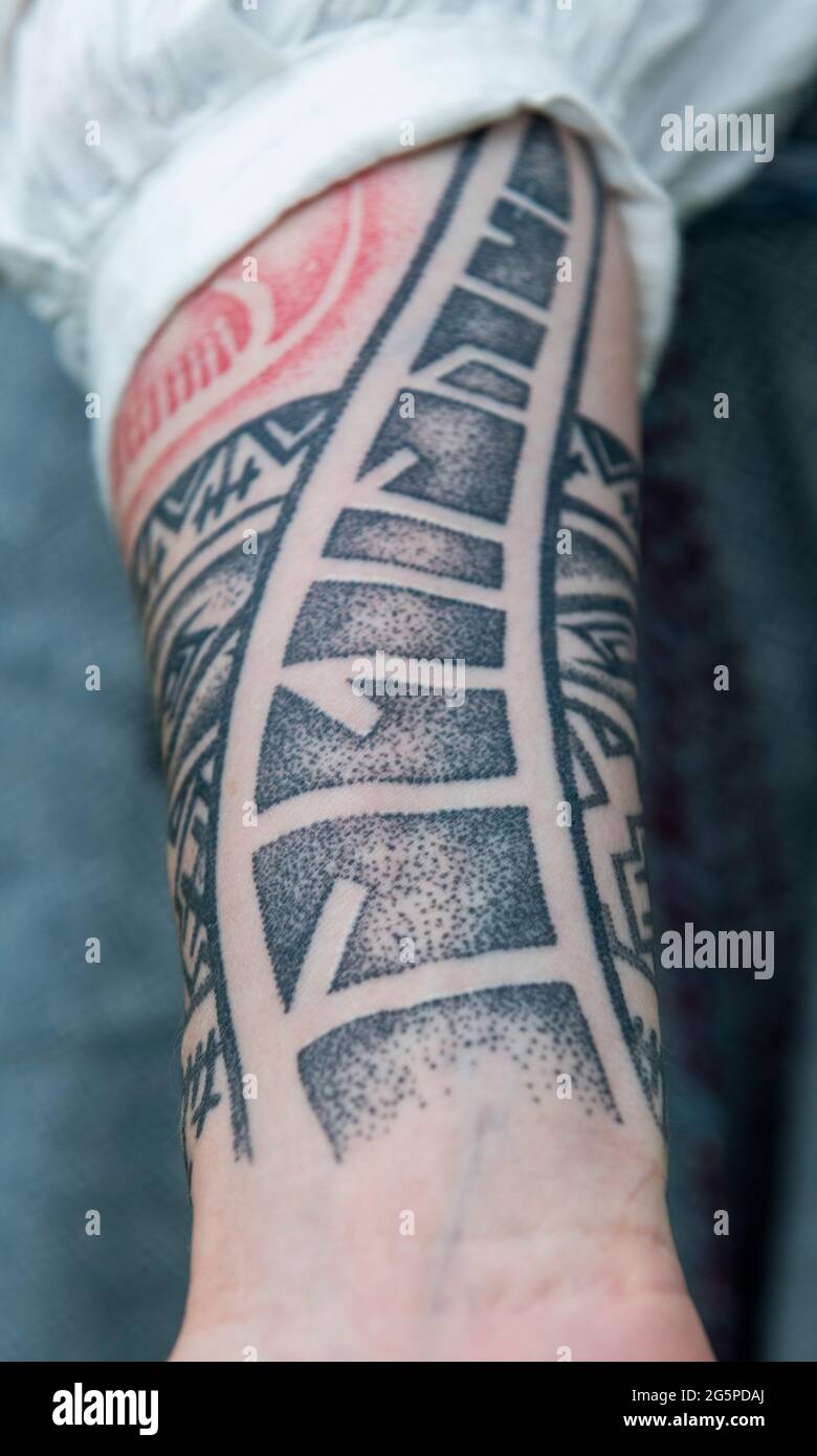 Tattoos on female arm in black and red ink Stock Photo