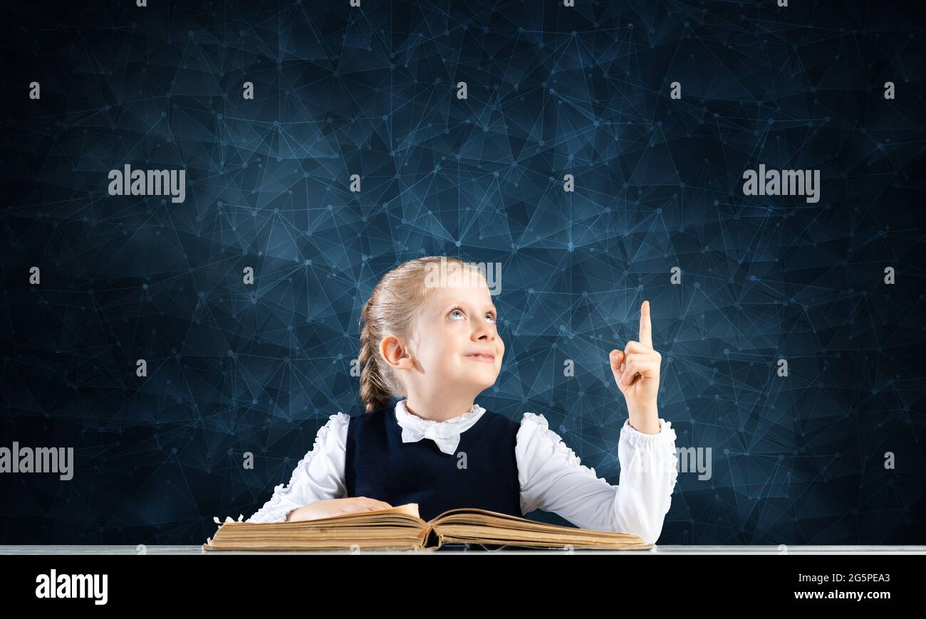 Smiling little girl sitting at desk with open book Stock Photo - Alamy