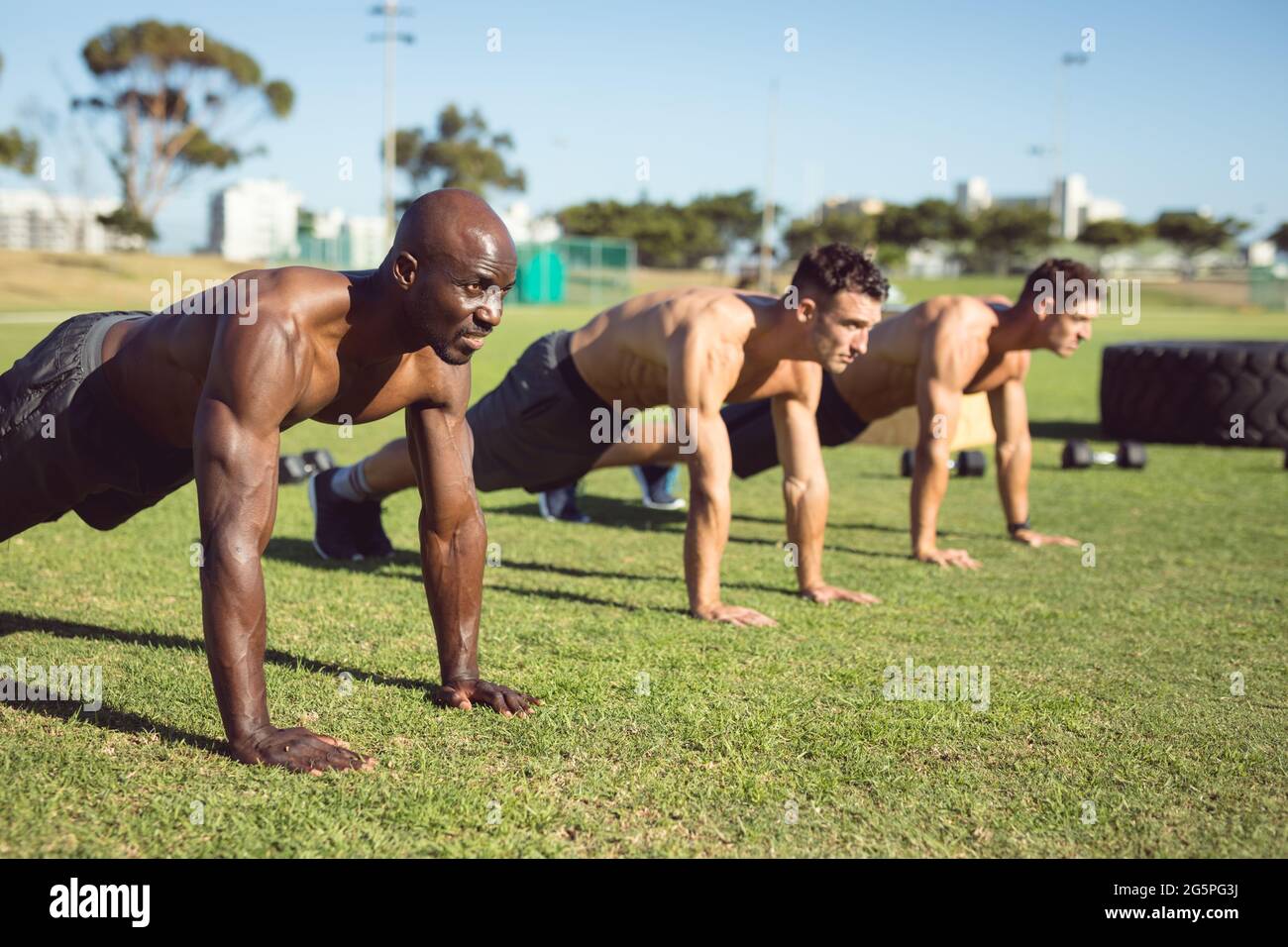Diverse group of muscular men doing push ups exercising outdoors