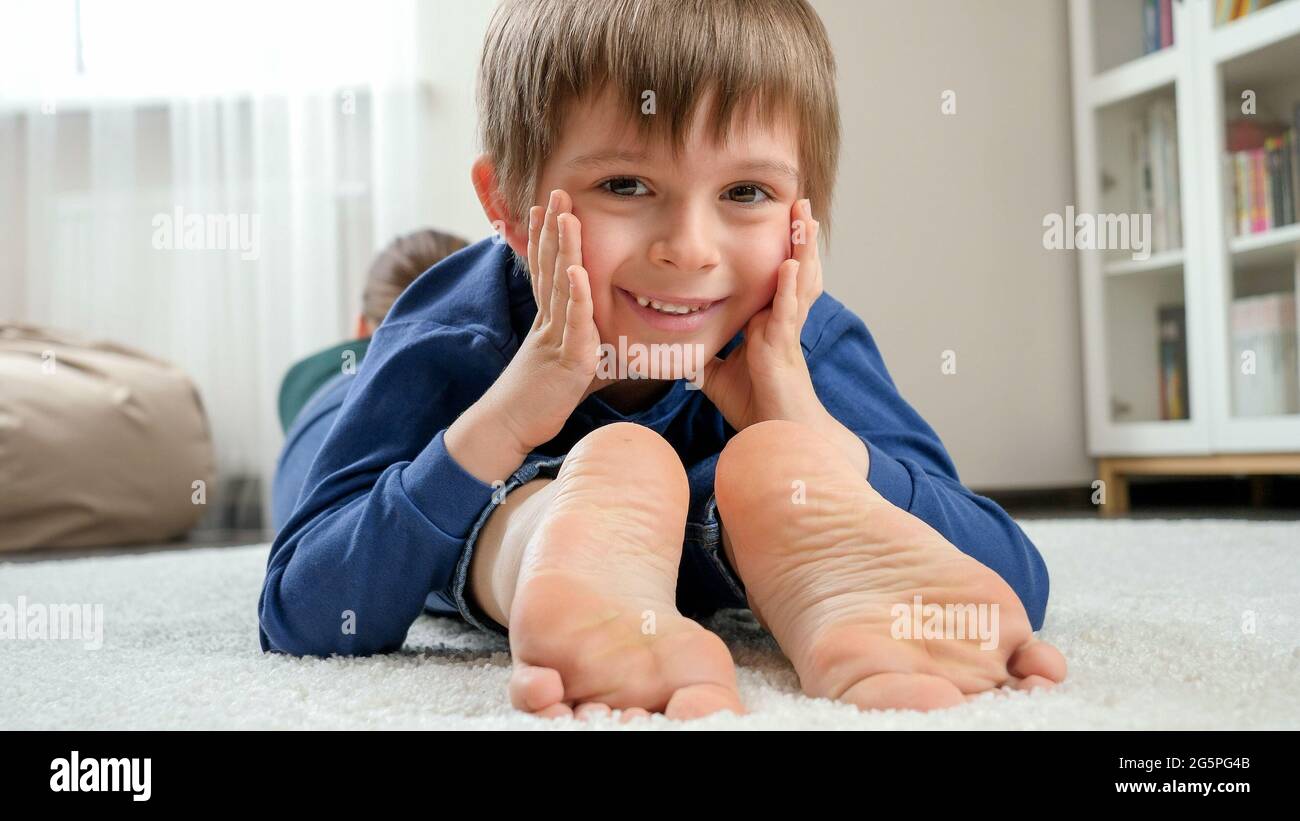 Portrait of happy smiling boy lying on mother's feet and looking in camera. Family having fun and playing together Stock Photo