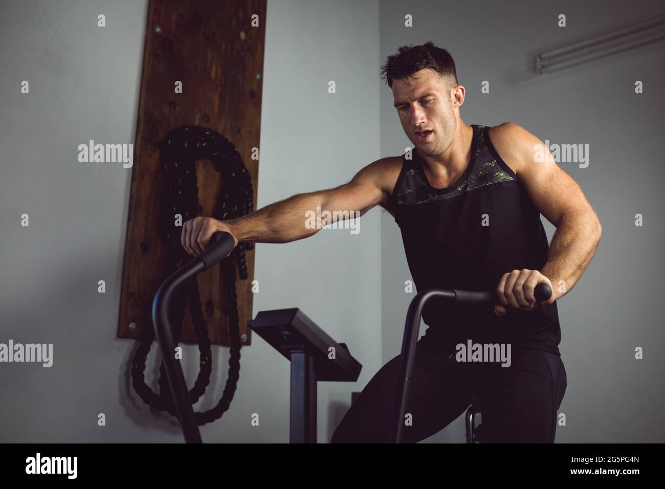 Fit caucasian man exercising at gym, using cross trainer Stock Photo