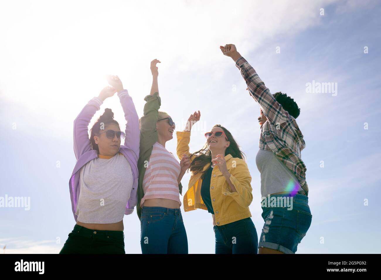 Happy group of diverse female friends having fun, with hands in the air Stock Photo