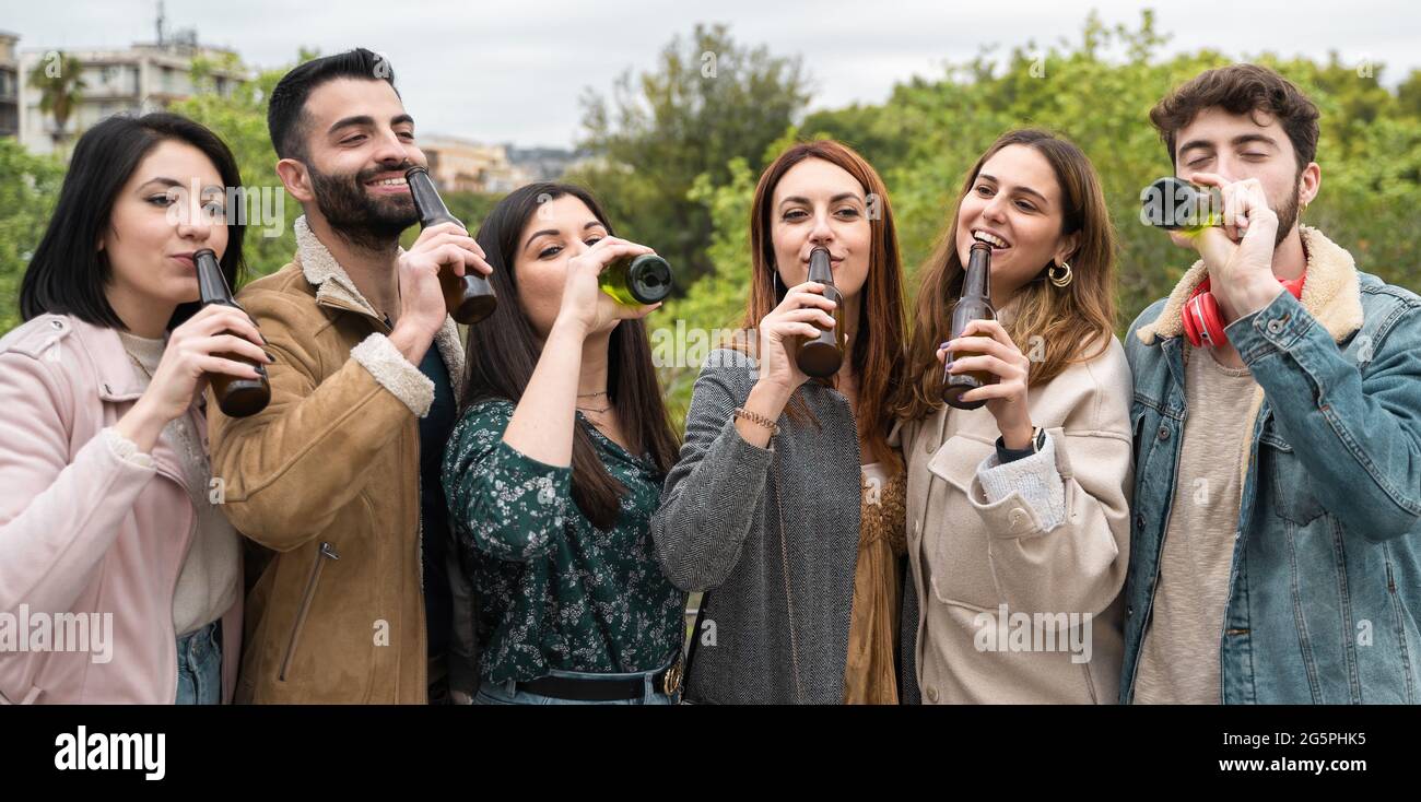 Young people drinking bottled beers in the nature. Friends having fun drinking together in the park lifestyle concept. Stock Photo