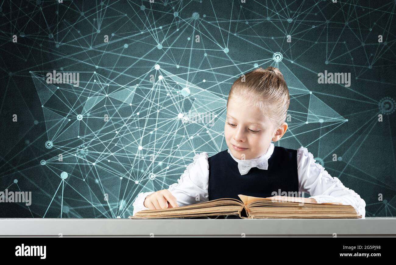 Smiling little girl sitting at desk with open book Stock Photo - Alamy