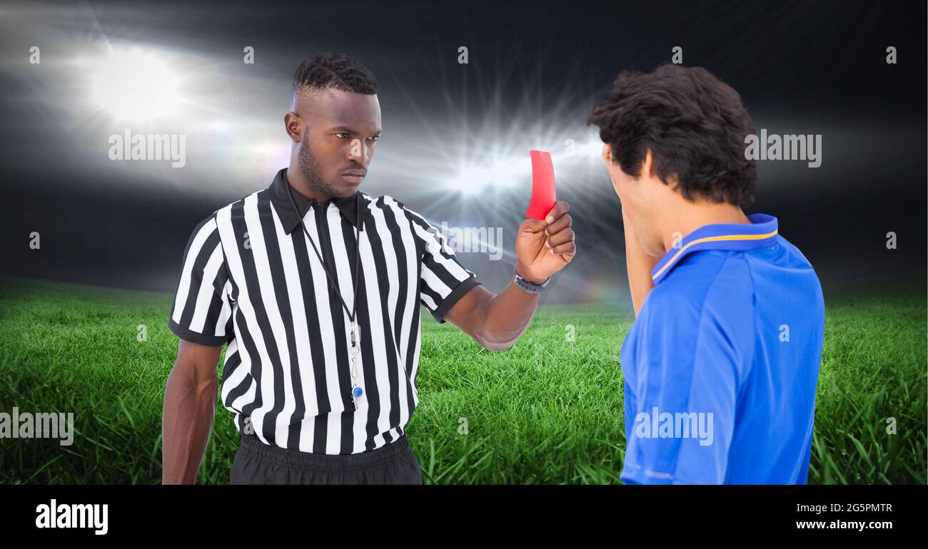 Composition of male referee with yellow card and player at football stadium Stock Photo