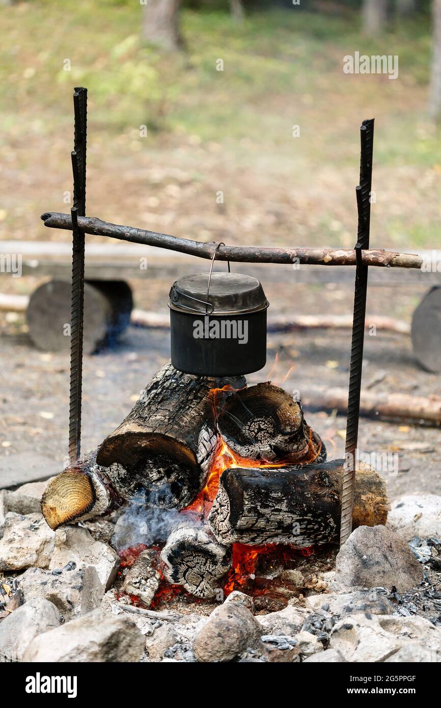 Camp fire, cooking dinner outdoors at the nature, pot over bonfire Stock Photo