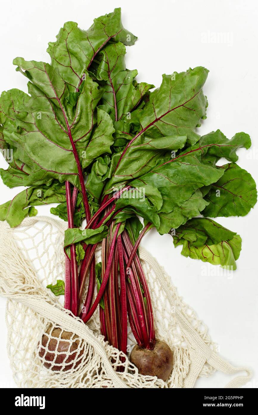 Trendy string bag with fresh young beetroot and haulm over light white ...