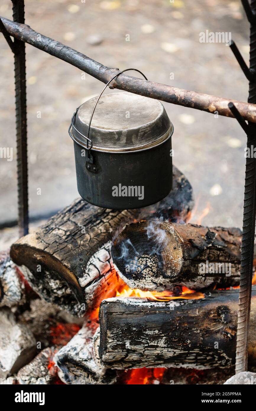 Camp fire, cooking dinner outdoors at the nature, pot over bonfire, close-up Stock Photo