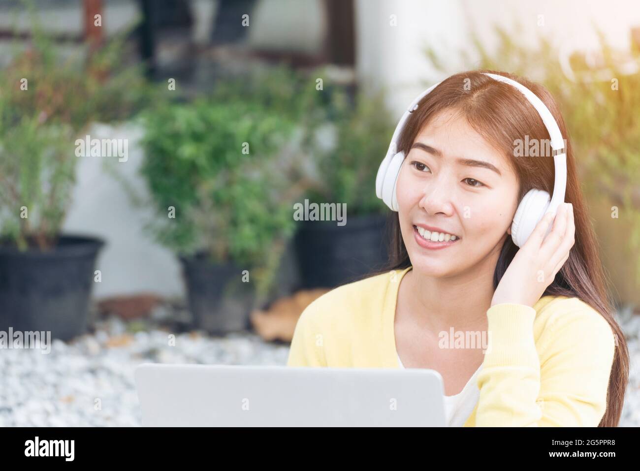 Young beautiful woman with happy face while listen to music from headphone and working on laptop. woman with technology lifestyle. Music happy life wi Stock Photo