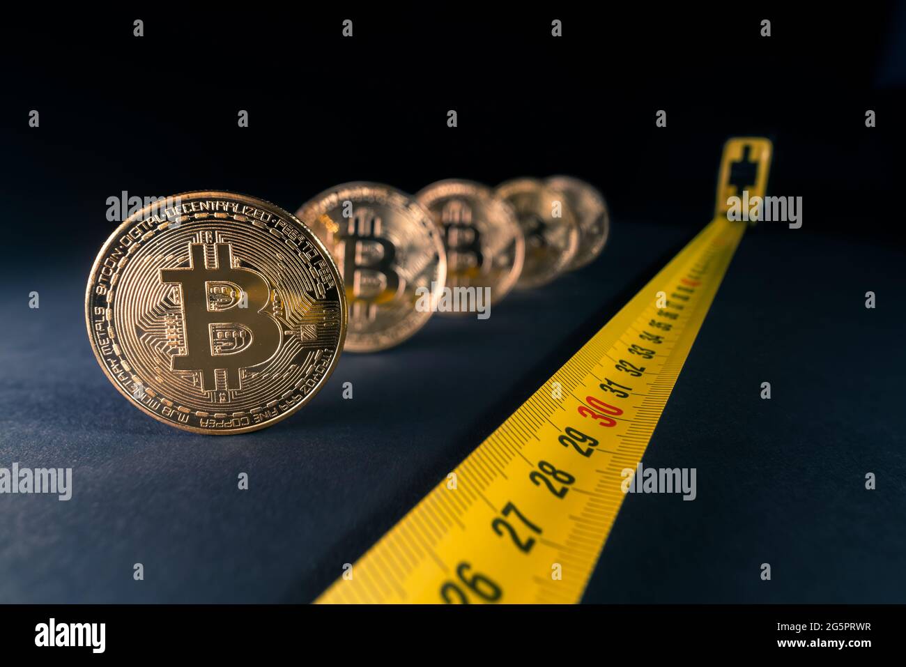 Concept for bitcoin crisis, price fluctuations, bitcoin price falling down to 30 thousands dollars. Golden bitcoins with a tape measure next to them w Stock Photo