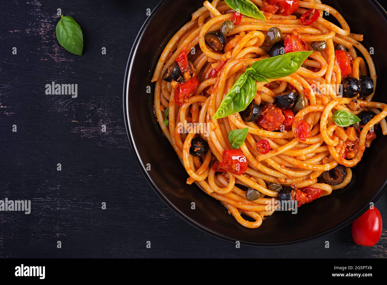 Spaghetti alla puttanesca - italian pasta dish with tomatoes, black olives,  capers, anchovies and basil. Top view, flat lay Stock Photo - Alamy