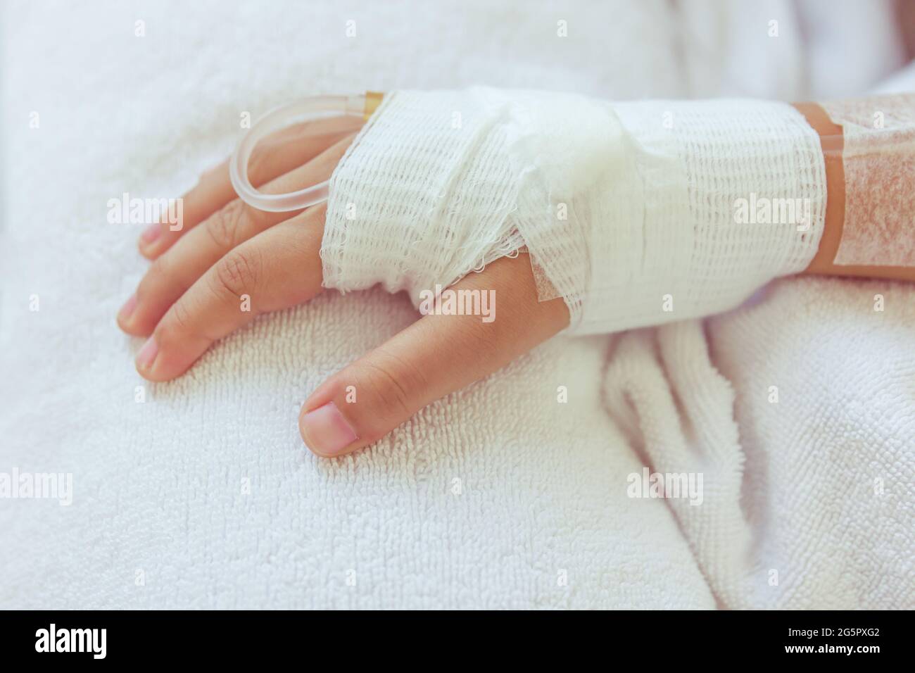 Close up of saline intravenous (iv) drip in a child's patient hand. Health care and people concept. Vintage style. Stock Photo