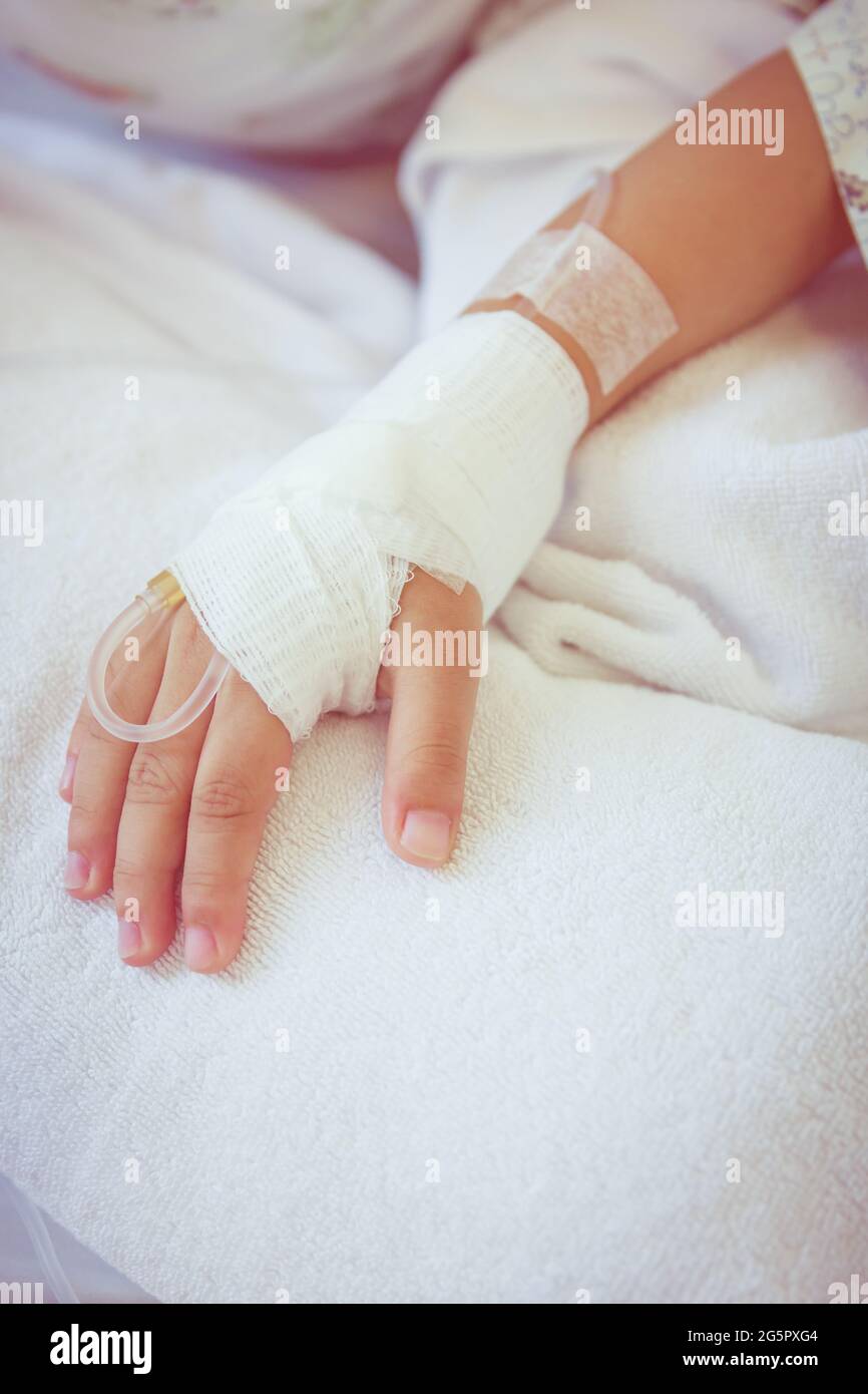 Close up of saline intravenous (iv) drip in a child's patient hand. Health care and people concept. Vintage style. Stock Photo