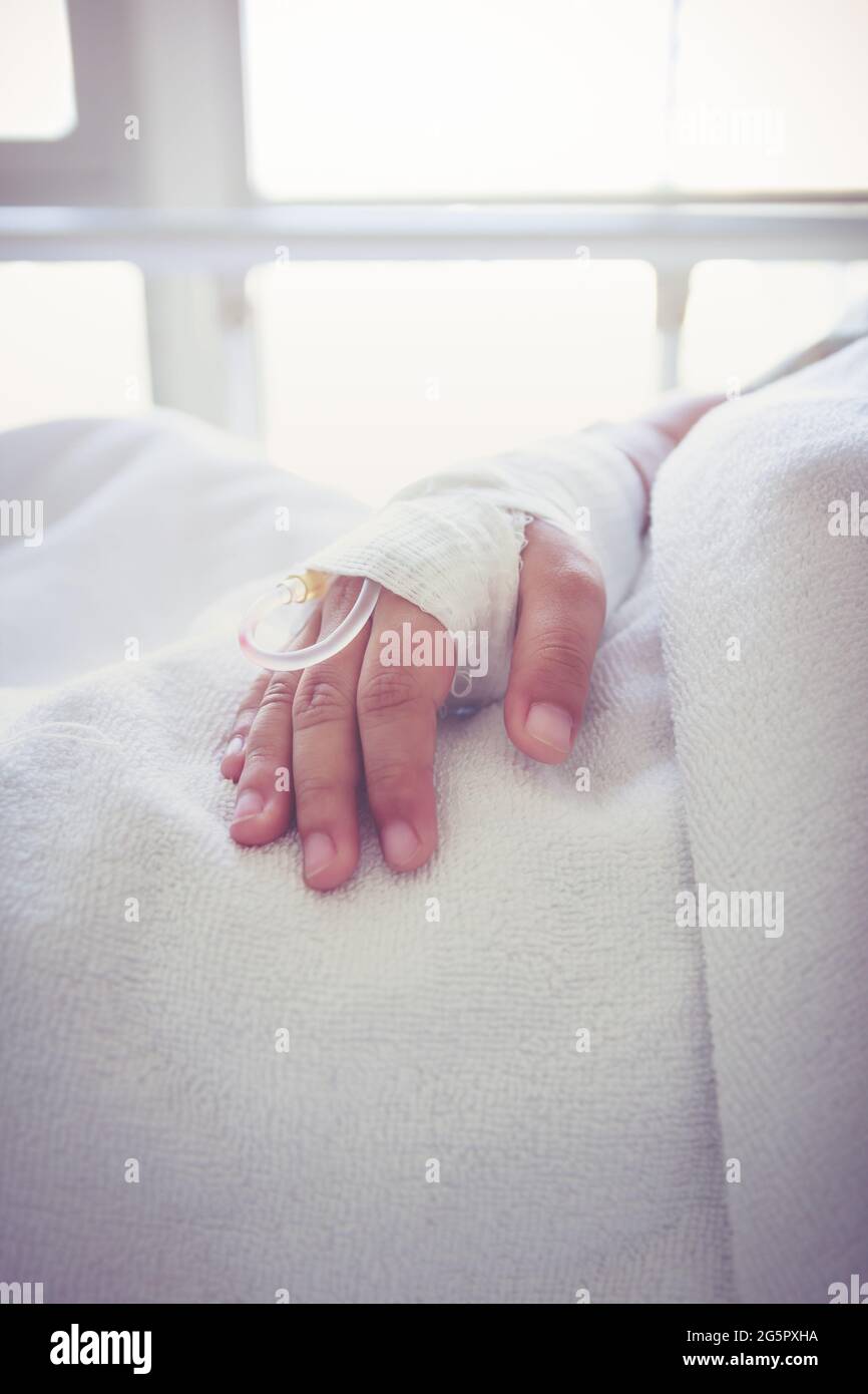 Close up of saline intravenous (iv) drip in a child's patient hand. Health care and people concept. Vintage tone. Stock Photo