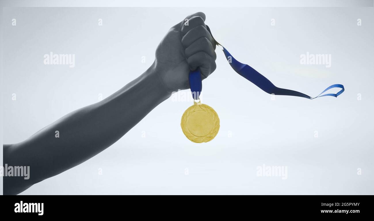 Black and white image of close up of hand holding a medal against grey background Stock Photo