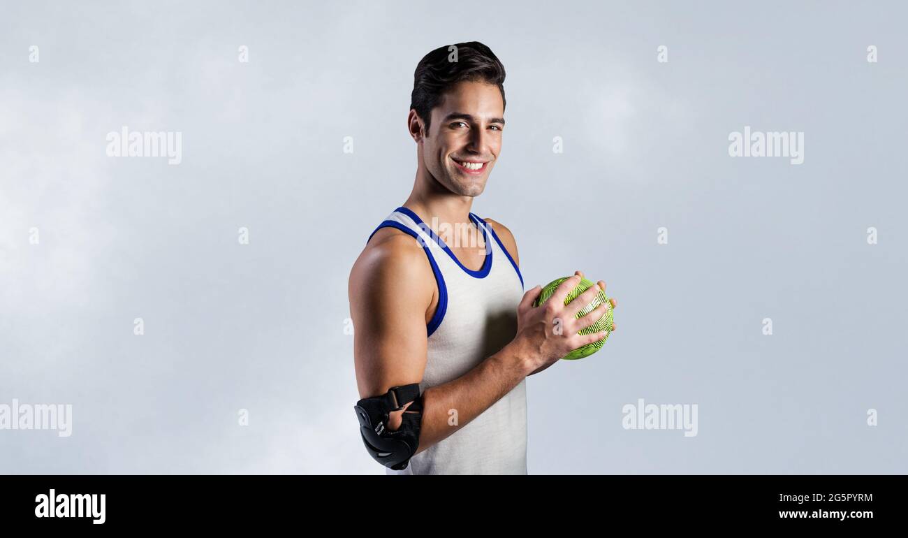 Portrait of caucasian male handball player holding a ball smiling against grey background Stock Photo