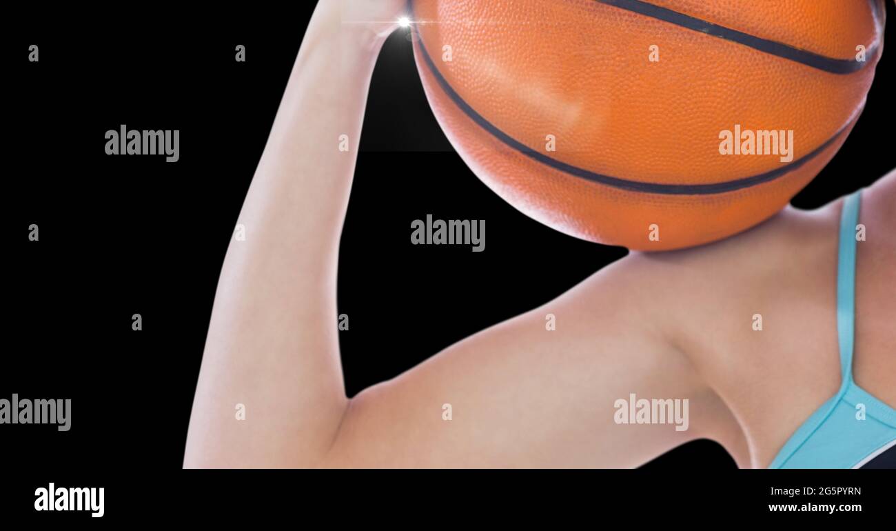 Close up view of female athlete holding a basketball against black background Stock Photo