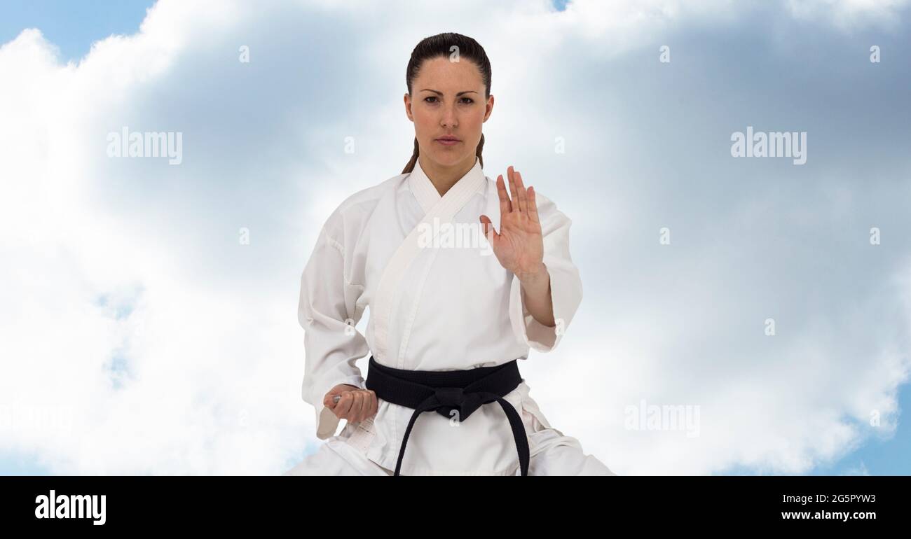 Digital composite image of caucasian female marital artist with black belt against blue sky Stock Photo