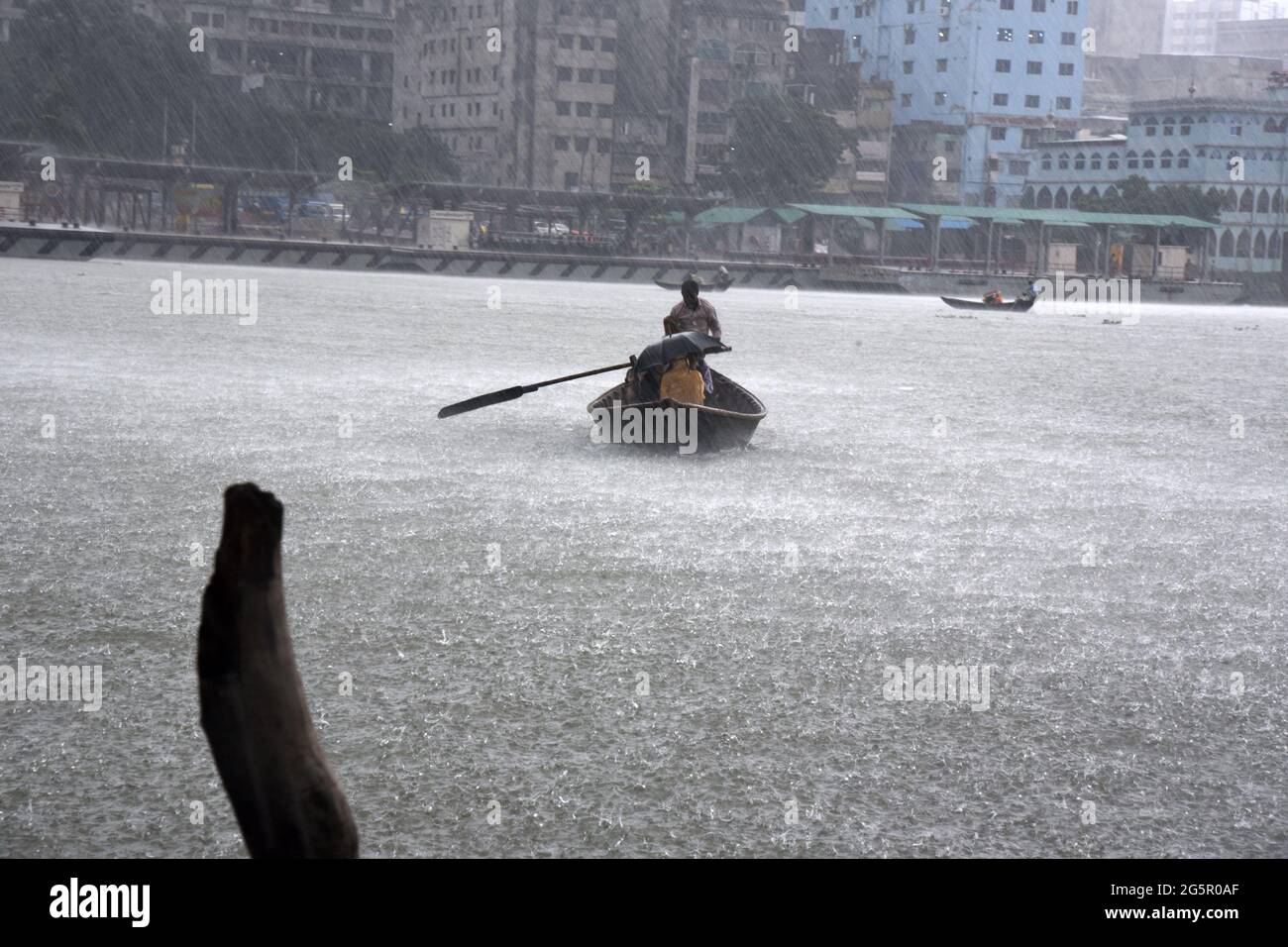 Bangladeshi commuters use boats to cross the Buriganga River during rain in Dhaka, Bangladesh on June 29, 2021. Stock Photo
