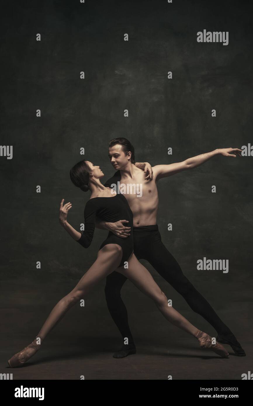 Beautiful graceful woman and man, ballet dancers in art performance dancing isolated over dark background Stock Photo