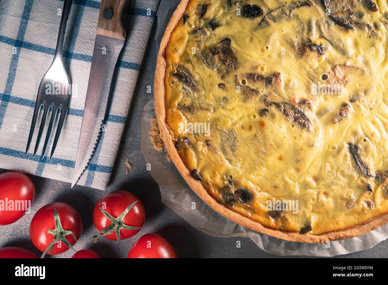 Top view of a freshly baked yellow quiche with mushrooms still on a ...