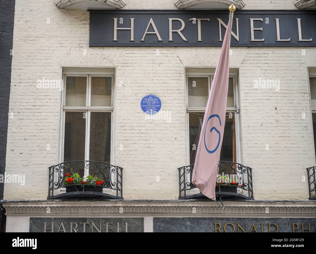 Bruton Street, London, UK. 29 June 2021. An English Heritage Blue Plaque dedicated to Court Dressmaker Sir Norman Hartnell at 26 Bruton Street, Mayfair, installed in 2005. Credit: Malcolm Park/Alamy Live News Stock Photo