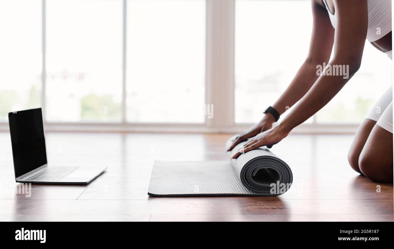 Young black woman unrolling yoga mat on floor near pc Stock Photo Alamy