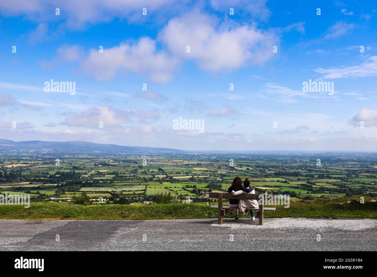 Two friends sitting in a bench near the edge of the road at Vee Pass in the Knockmealdown mountains in Clogheen county Tipperary, Ireland Stock Photo